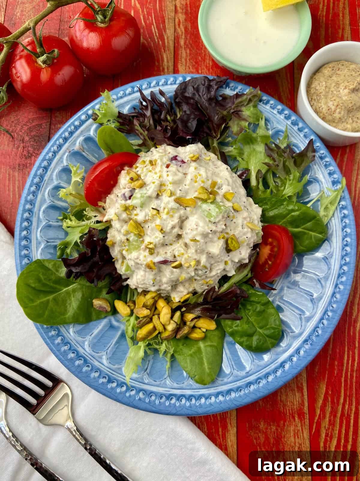Pistachio and Poppy Seed Chicken Salad Recipe with Citrus Dressing 2 Pistachio Chicken Salad on a bed of greens on blue plate.