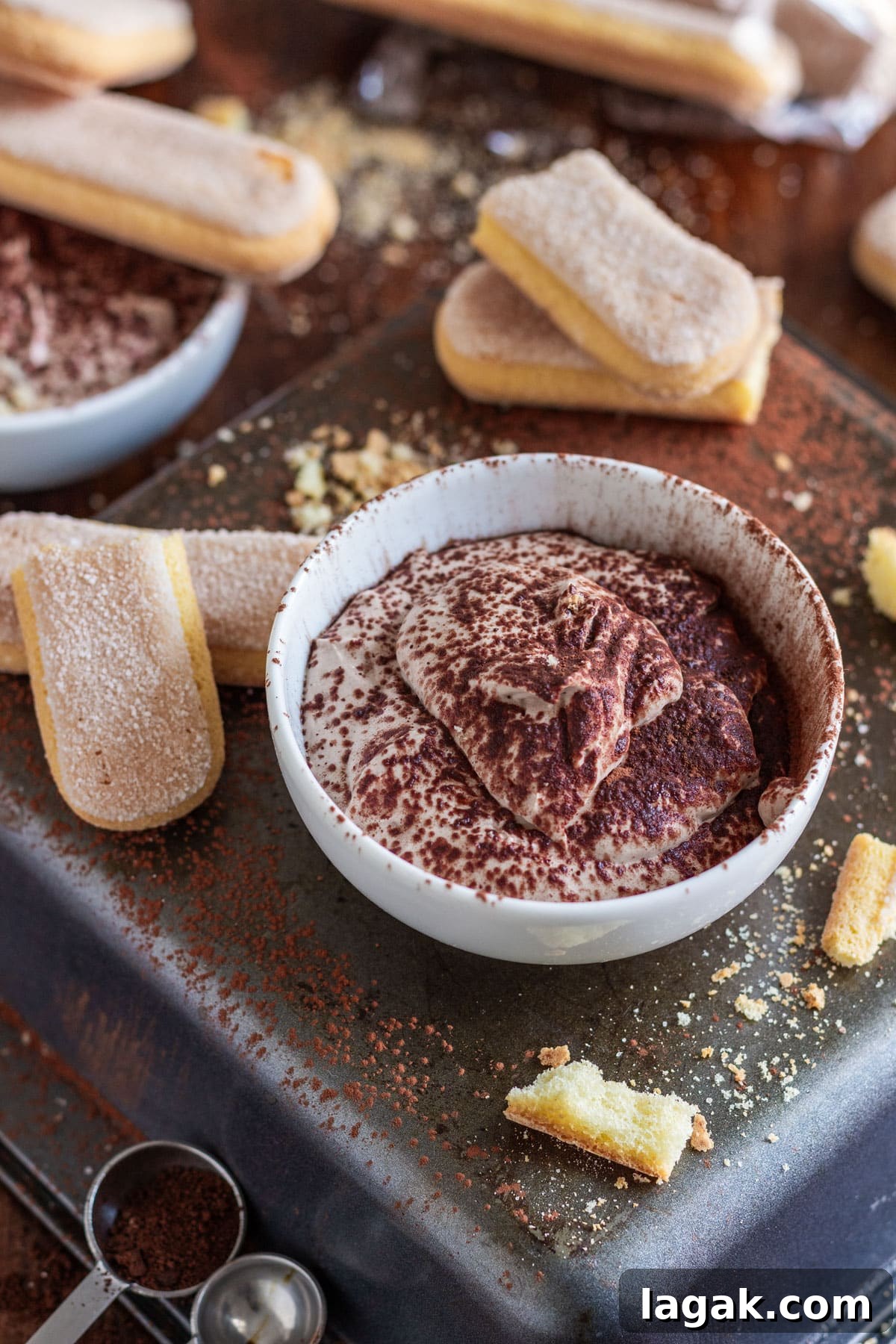 Quick Tiramisu Dip — Ready in 5 Minutes 4 A bowl of tiramisu dessert dip with ladyfingers, cocoa powder and crumbs scattered around.