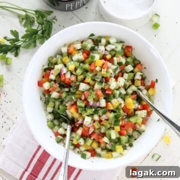 Mediterranean Cucumber and Bell Pepper Salad with Feta and Herbs 8 A white bowl of colorful cucumber and red bell pepper salad.