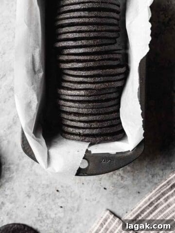 A row of round dark chocolate cookies in a parchment lined pan.