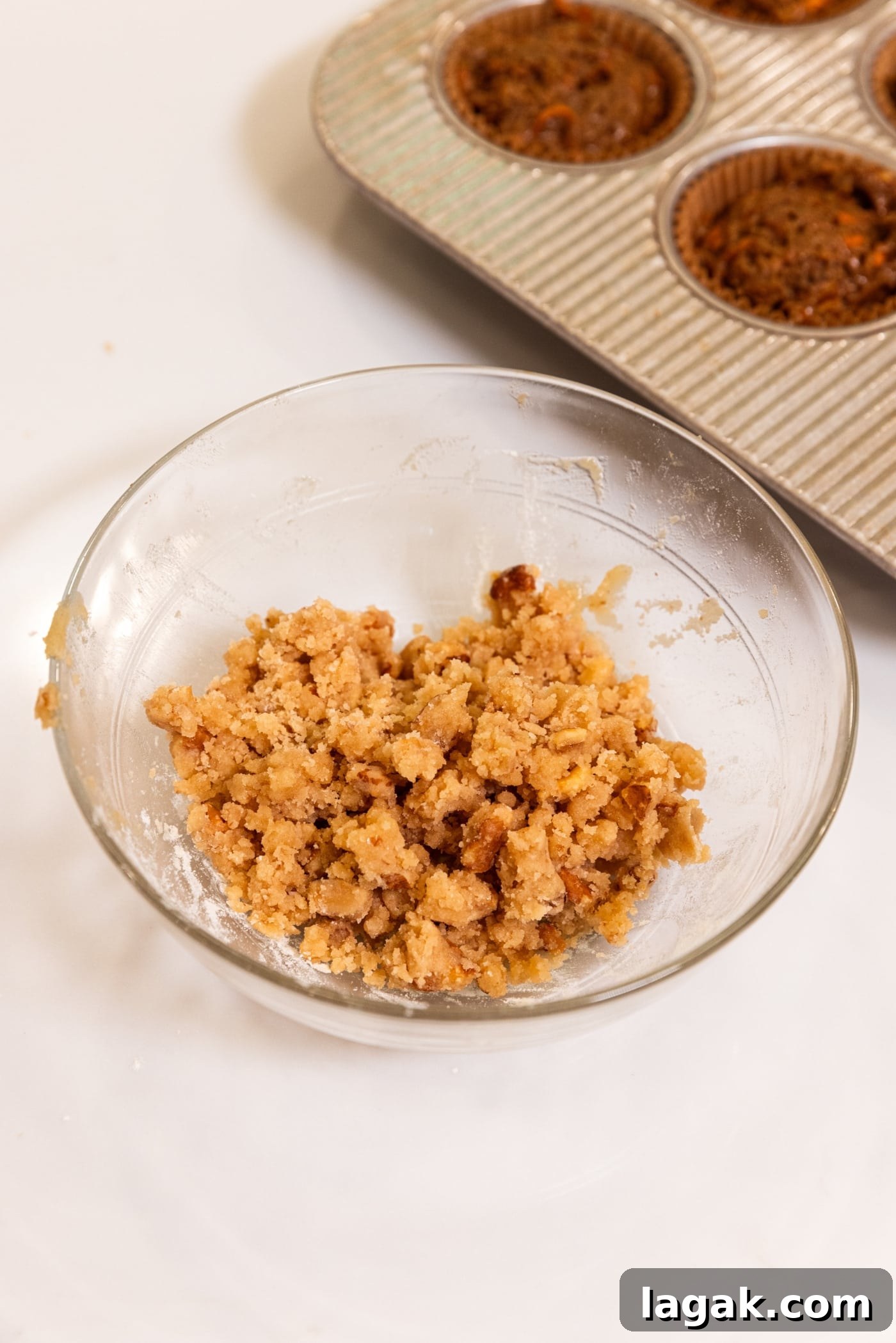Warm Spiced Carrot Muffins with Cinnamon and Ginger 12 Glass bowl filled with streusel topping after being mixed together with nuts showing.