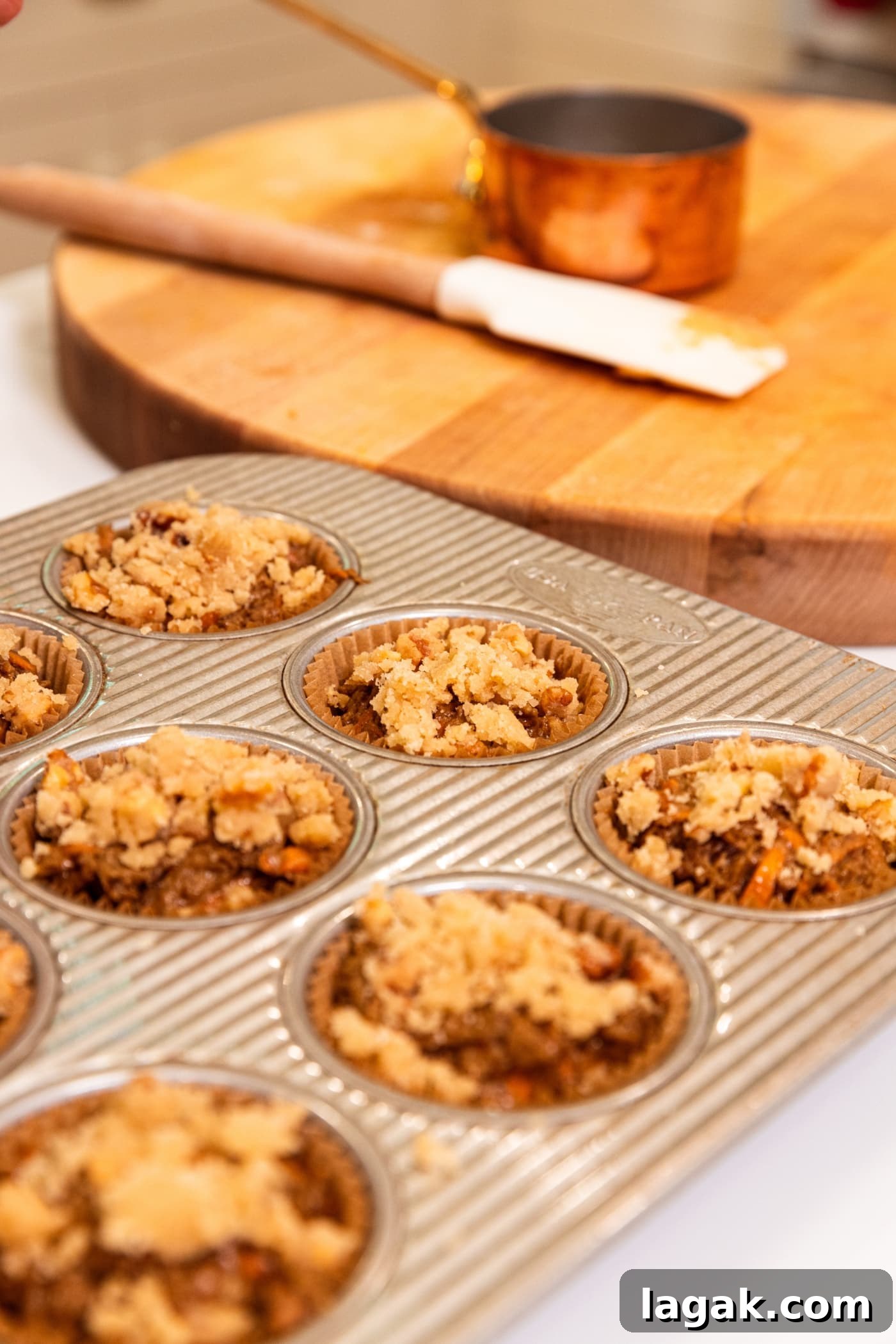 Warm Spiced Carrot Muffins with Cinnamon and Ginger 14 Streusel resting on top of unbaked muffins in muffin tin.