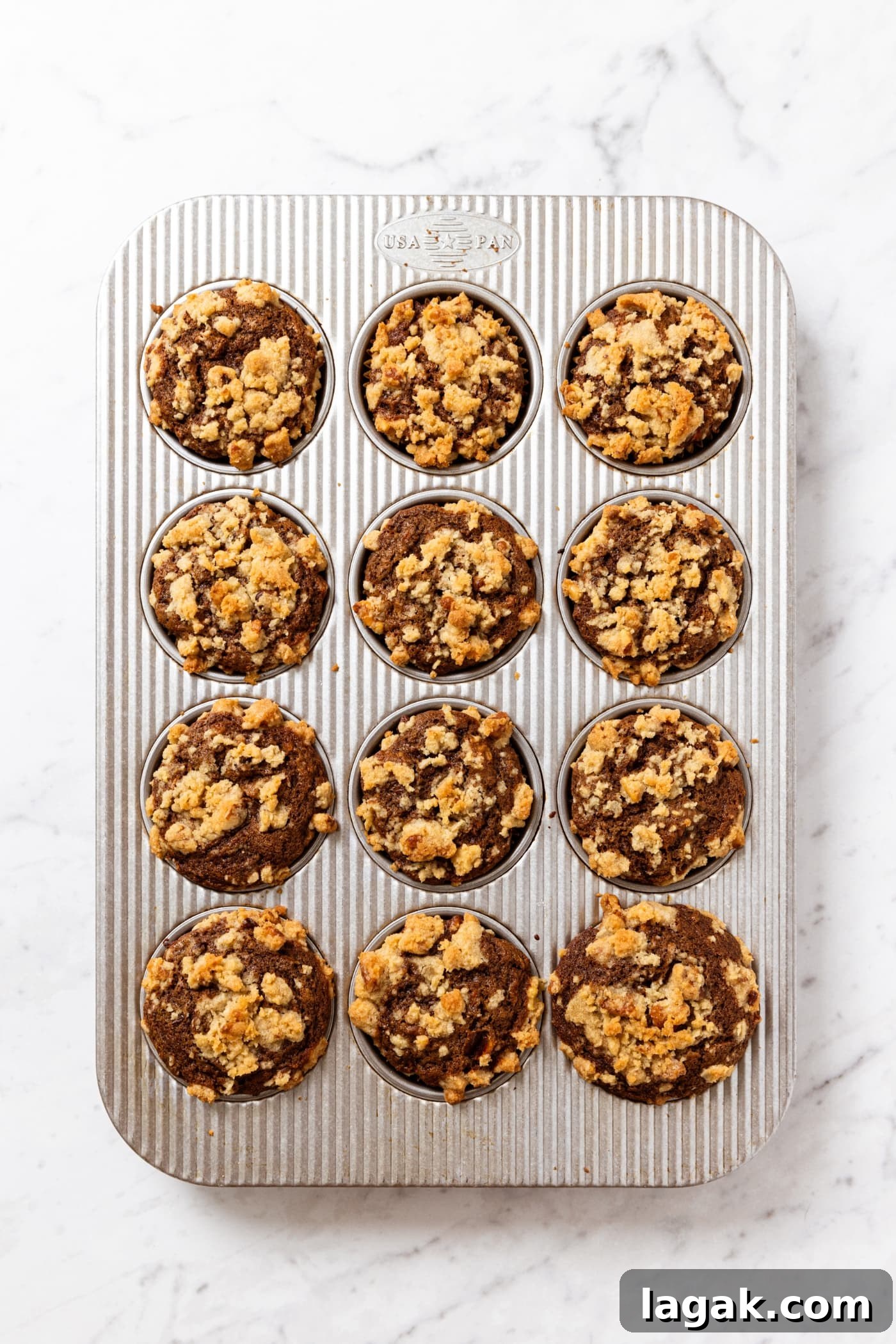Warm Spiced Carrot Muffins with Cinnamon and Ginger 16 Metal muffin tin on white marble surface with baked spiced carrot muffins right after coming out of the oven.