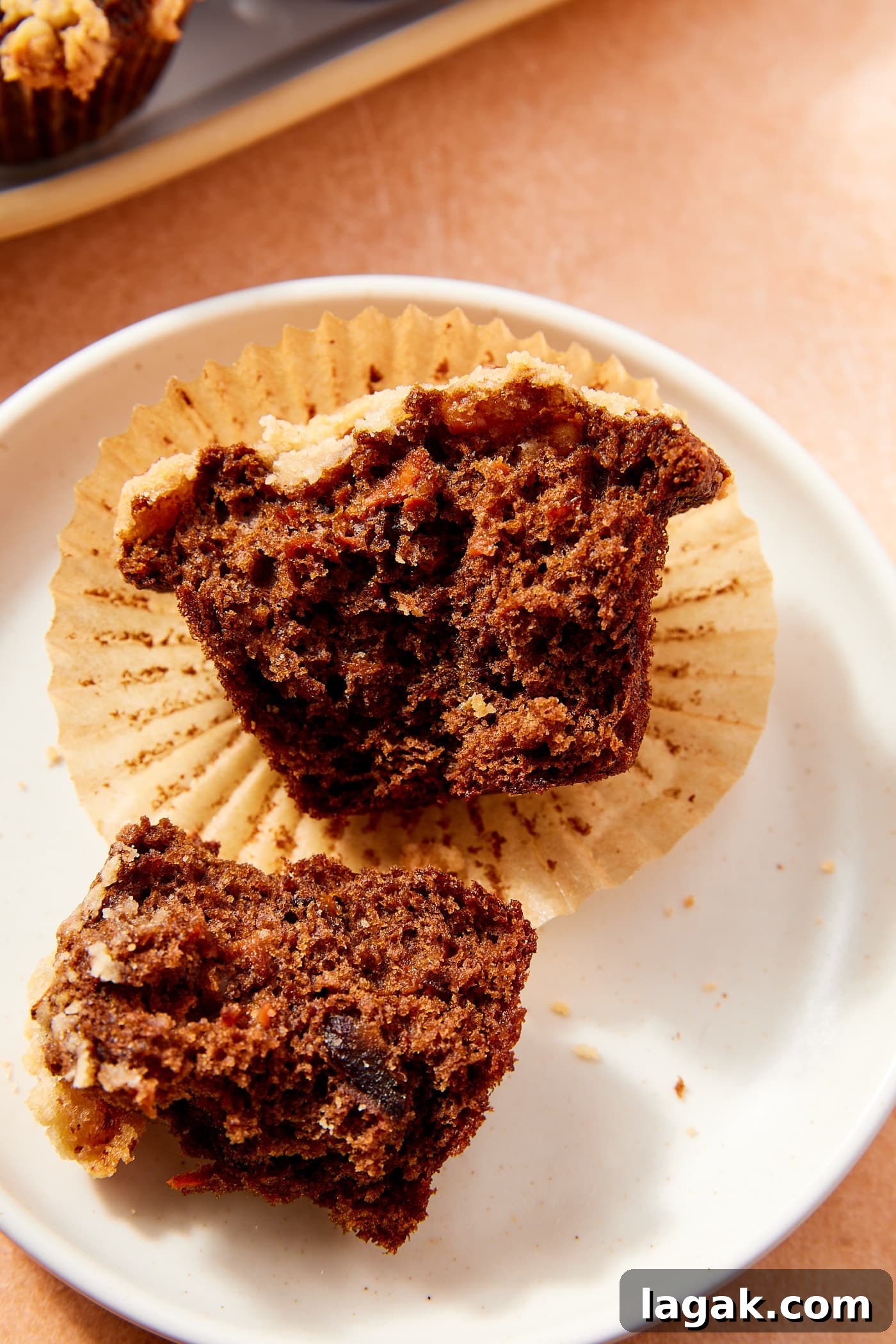 Warm Spiced Carrot Muffins with Cinnamon and Ginger 3 Dark colored spiced carrot muffin with streusel topping resting on plate after being torn in half to show interior.