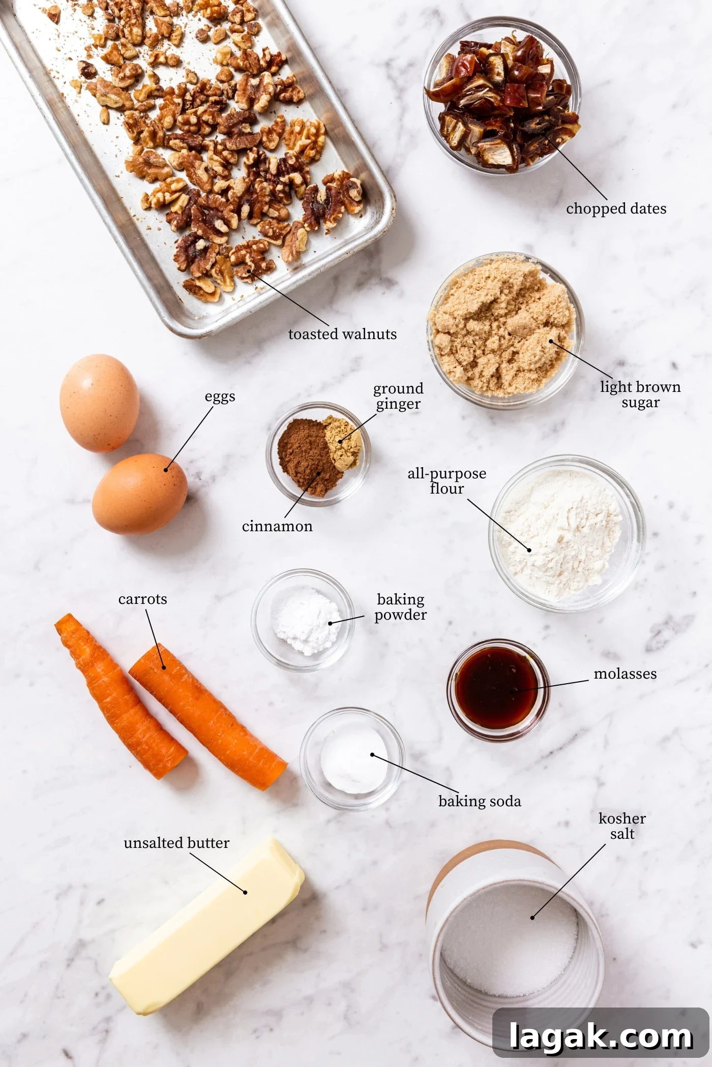 Warm Spiced Carrot Muffins with Cinnamon and Ginger 4 White marble surface filled with all ingredients needed to make spiced carrot muffins including raw carrot, walnuts, eggs, spices, and more.