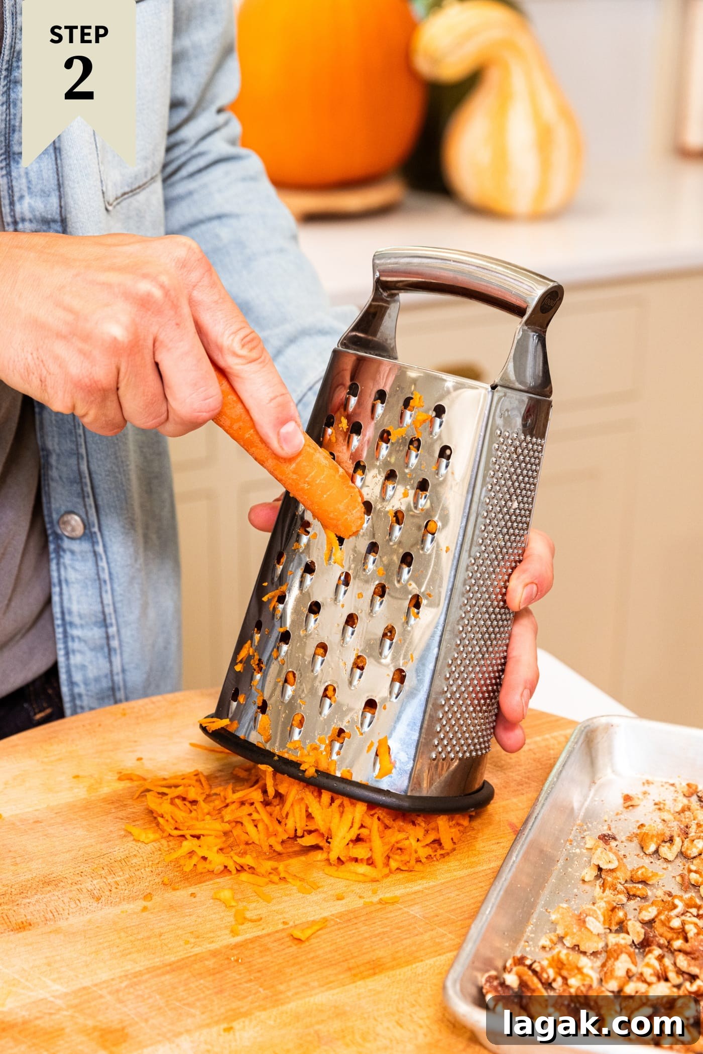 Warm Spiced Carrot Muffins with Cinnamon and Ginger 7 Hand grating carrot on grater onto wood cutting board with pieces of carrot underneath.