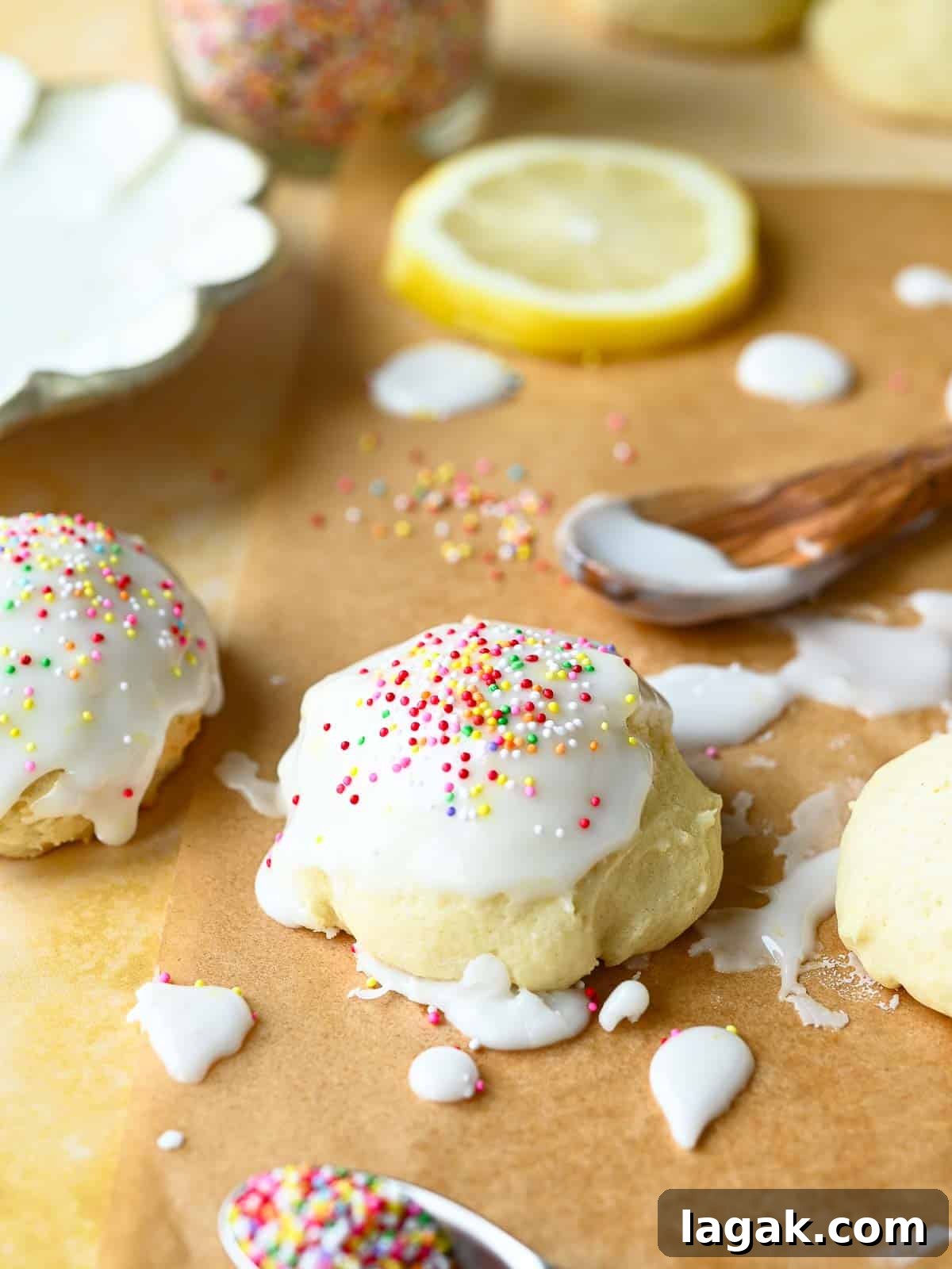 Italian Lemon Drop Cookies Recipe — Zesty Citrus Biscotti-Style Treat 11 Italian lemon drop cookies with icing and sprinkles on parchment paper with lemons and sprinkles in the background.