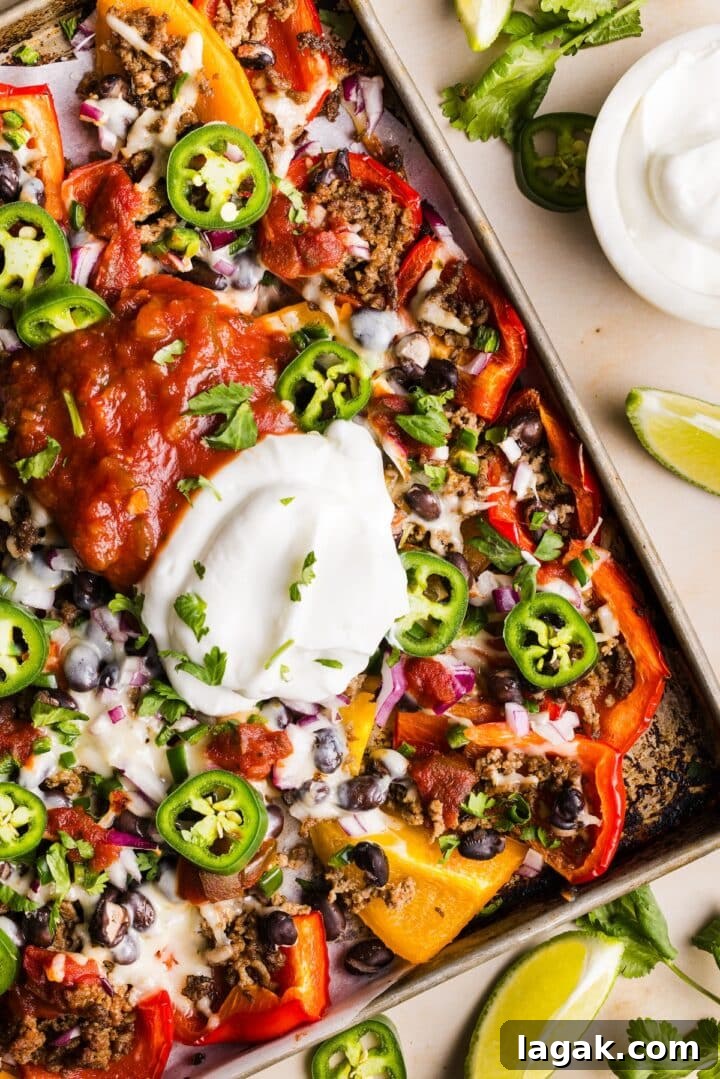 Bell Pepper Nachos with Zesty Cheese and Fresh Toppings 2 Healthy bell pepper nachos topped with a big dollop of greek yogurt and salsa, on a sheet tray