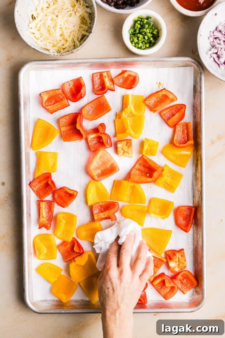 Bell Pepper Nachos with Zesty Cheese and Fresh Toppings 5 Woman's hand dabbing extra moisture out of bell pepper nacho slices that have been baked in the oven on a sheet pan