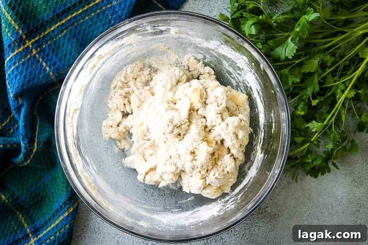 Rosemary Parmesan Loaf Recipe: Crispy Crust, Savory Interior 3 Cheese and rosemary added to a bowl of bread dough.