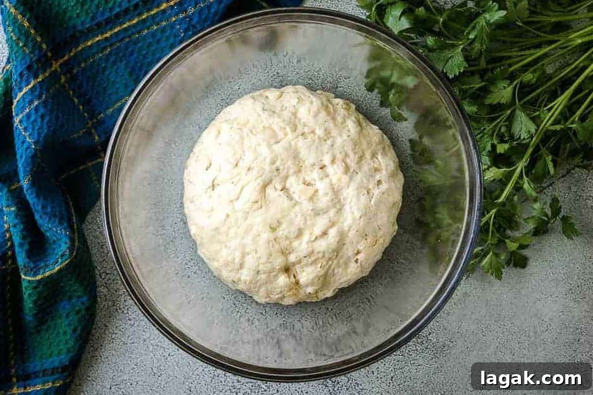 Rosemary Parmesan Loaf Recipe: Crispy Crust, Savory Interior 4 Risen bread dough in a glass bowl.