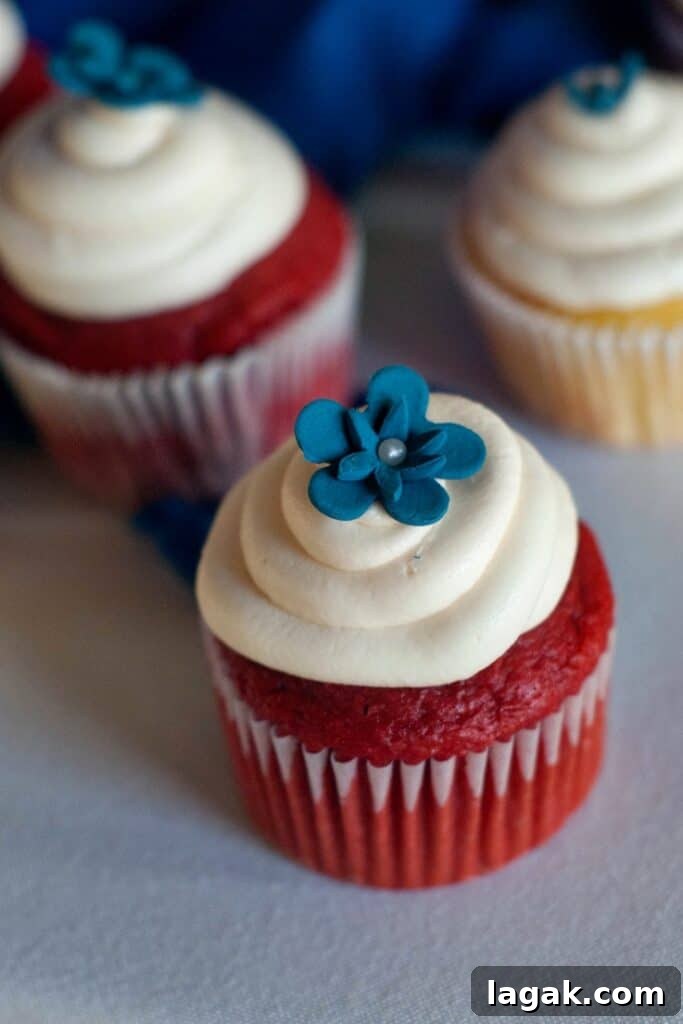 Classic Red Velvet Cupcakes with Cream Cheese Frosting 2 Two Easy Red Velvet Cupcakes with cream cheese frosting and a blue decorative flower on top.