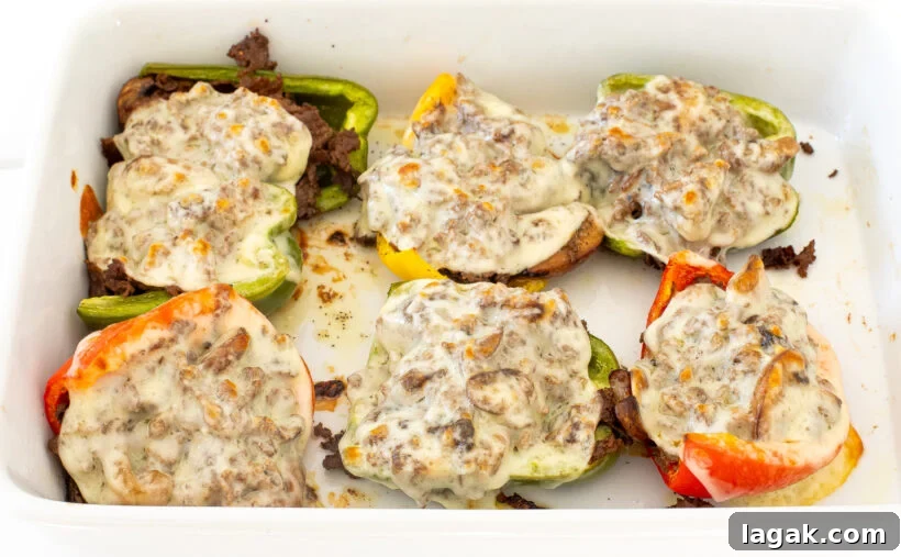 Philly Cheesesteak Stuffed Bell Peppers: Savory Low-Carb Dinner 12 Melted cheese on top of stuffed bell peppers in a white baking pan.