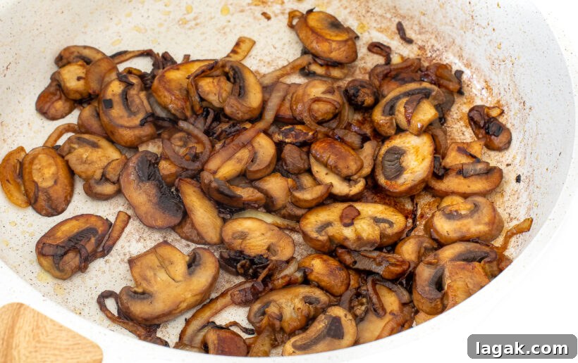 Philly Cheesesteak Stuffed Bell Peppers: Savory Low-Carb Dinner 7 Mushrooms in a white frying pan.