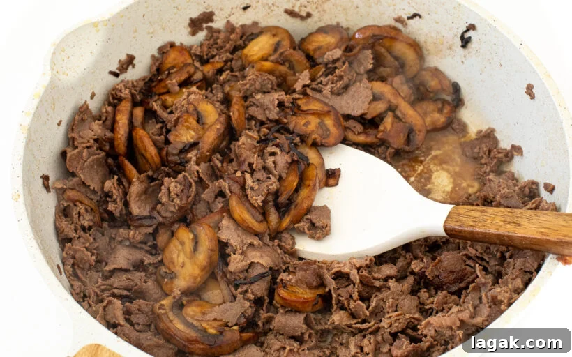 Philly Cheesesteak Stuffed Bell Peppers: Savory Low-Carb Dinner 9 Sliced beef in a frying pan with onions and mushrooms added.