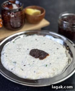 Tangy South Indian Ginger Pickle (Inji Thokku) Recipe 4 Spicy ginger pickle served on a silver plate with condiments in the background.