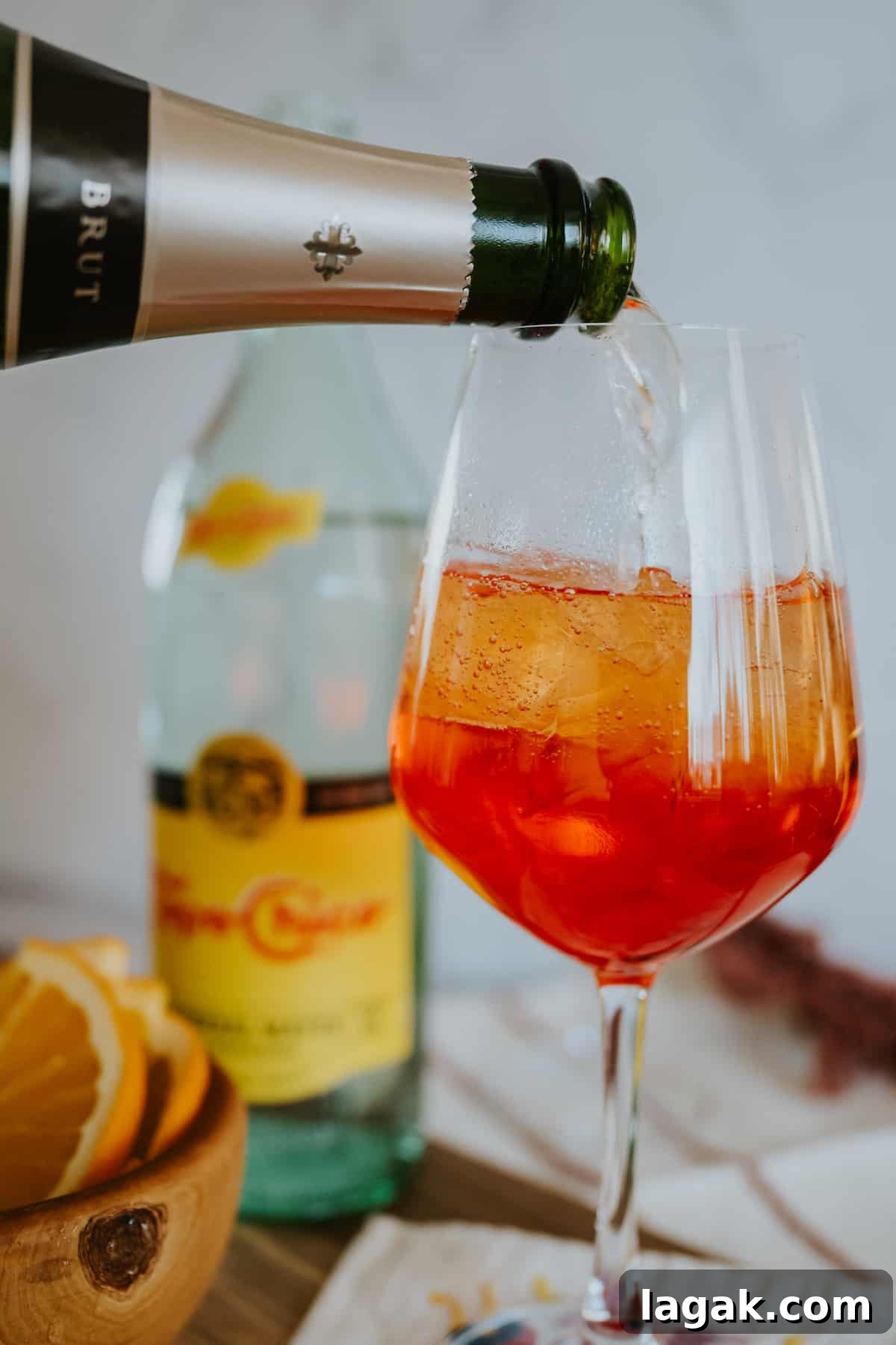 Classic Aperol Spritz Recipe: How to Make the Perfect Cocktail 5 process shot of pouring the cava into the glass with the aperol and ice.