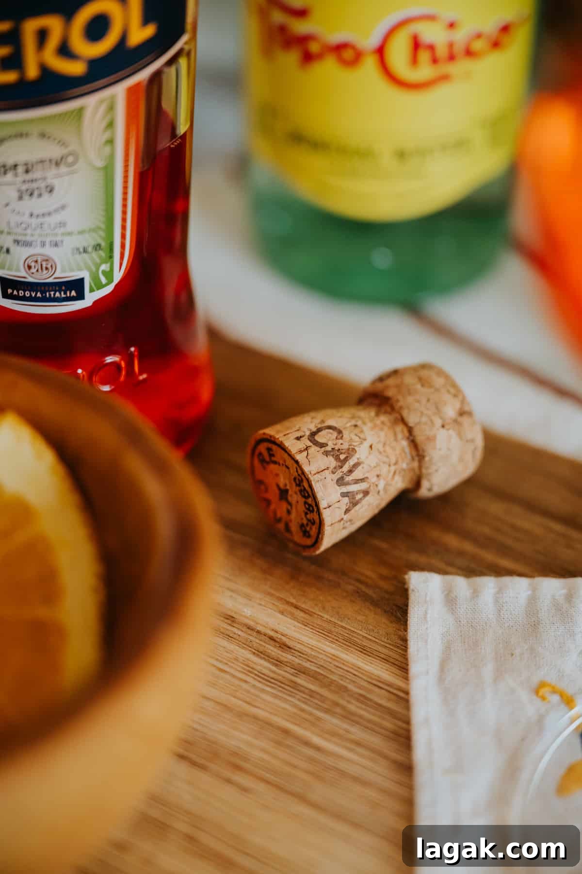 Classic Aperol Spritz Recipe: How to Make the Perfect Cocktail 8 artsy shot of the ingredients needed to make an Aperol spritz on a wooden cutting board.