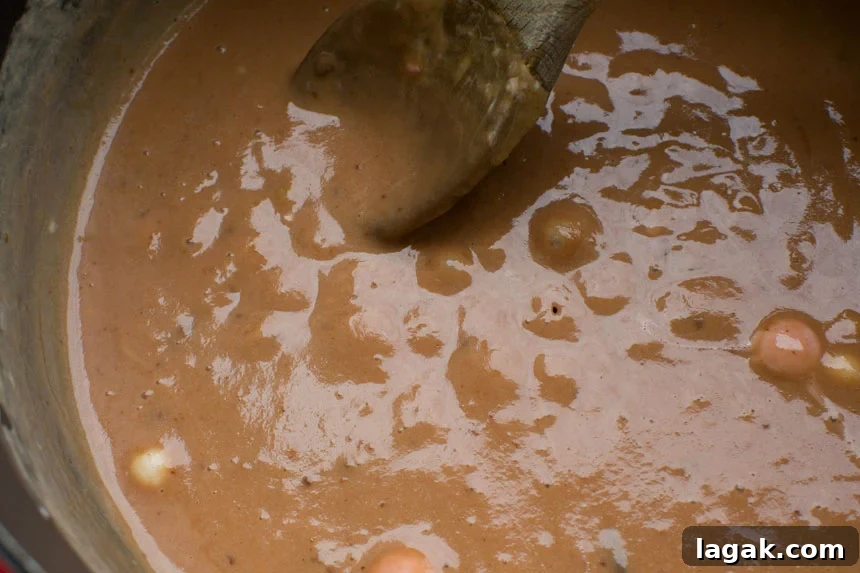 The caramel mixture for making peanut butter cheerio bars in a saucepan with a wooden spoon