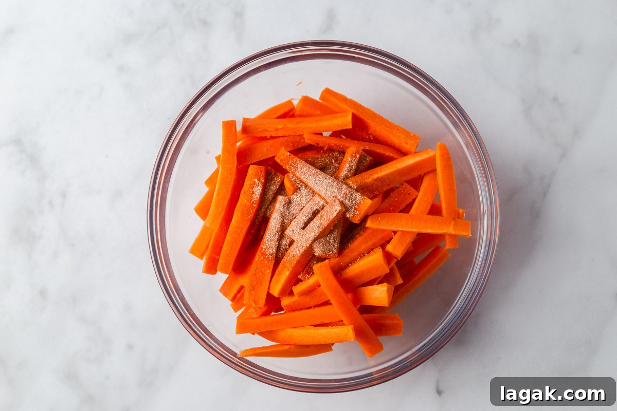 Crispy Air Fryer Carrot Fries Recipe for a Crunchy Snack 5 adding spices to carrot fries in a bowl.