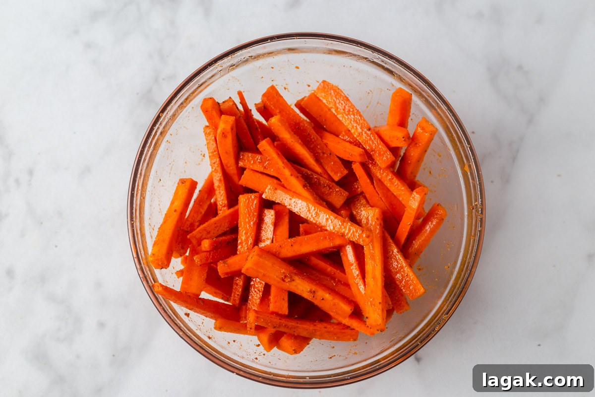 Crispy Air Fryer Carrot Fries Recipe for a Crunchy Snack 6 mixing the fries with oil and spices.