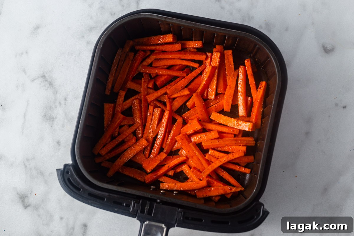 Crispy Air Fryer Carrot Fries Recipe for a Crunchy Snack 7 placing carrot fries in the air fryer.