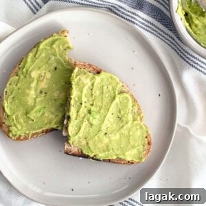 3-Ingredient Dunkin’ Style Avocado Toast Recipe 11 Avocado toast with flaky sea salt and cracked black pepper on a white plate