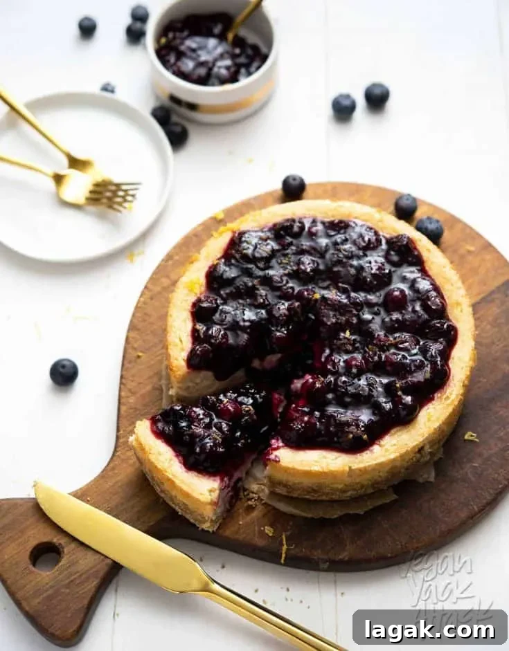 Blueberry cheesecake with a slice cut out of it, on a wood cheese board