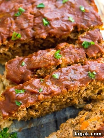 A loaf of gluten free meatloaf cut into pieces and garnished with fresh parsley.