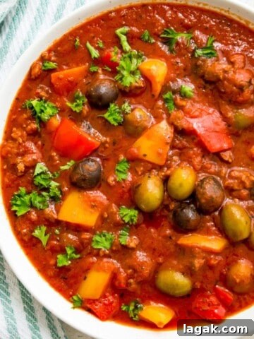 A bowl of healthy meat sauce garnished with fresh parsley.