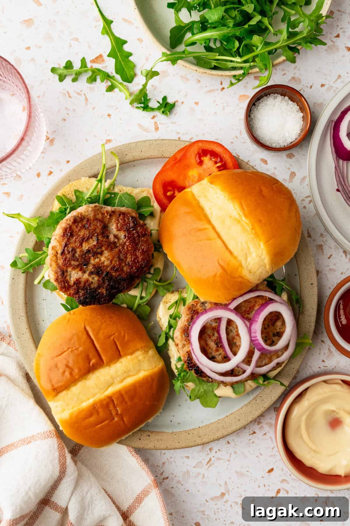 Juicy Ground Pork Burger Recipe for Flavorful Weeknight Meals 8 Pork burgers in buns topped with chopped onion, lettuce and sliced tomatoes.