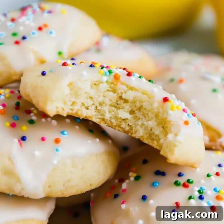 A pile of sour cream cookies where the one in the middle has a bite out of it exposing the cakey center of the cookie.