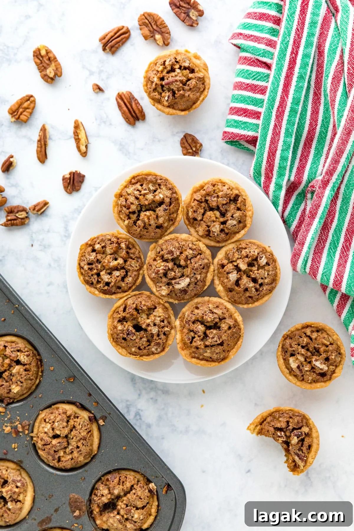 Grandma Rose’s Pecan Tassies Recipe for Perfect Bite-Sized Pies 9 An overhead image of a plate of pecan tassies with pieces of cookies, a pan of them and a red and green towel around it.
