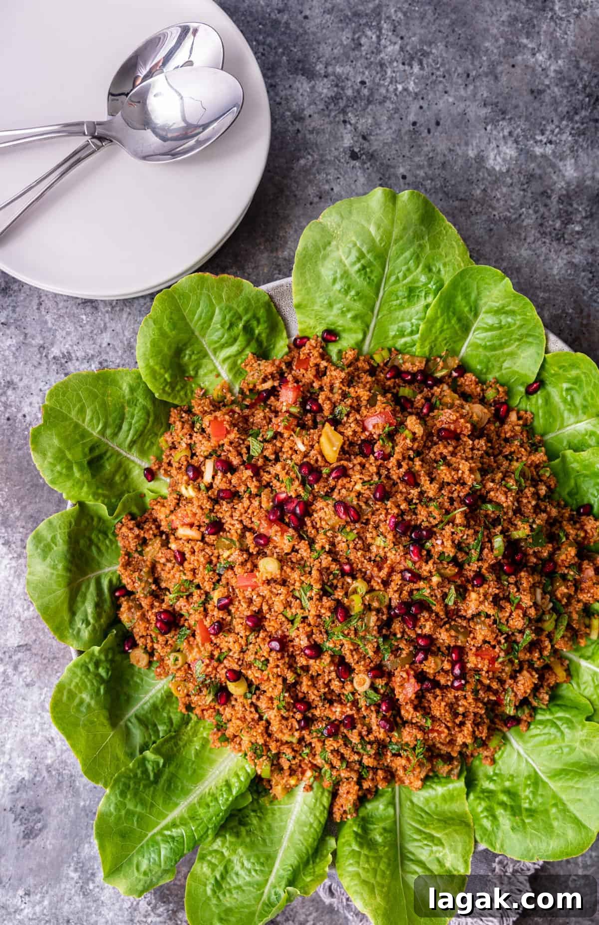 overhead: platter of turkish bulgur salad next to white serving plates and spoons