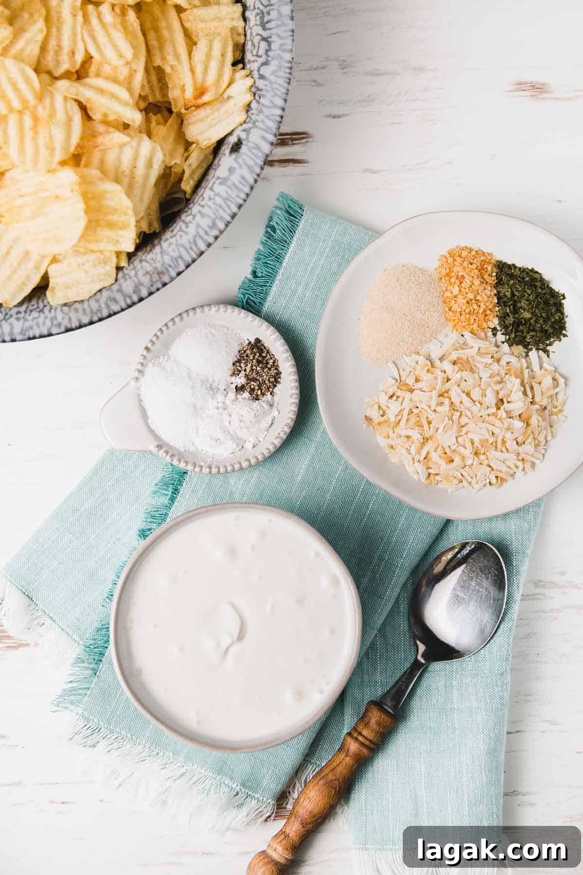 Gluten-Free French Onion Dip for Chips and Veggies 3 Dried spices for gluten-free onion soup mix measured out on small plates. A bowl of sour cream on a teal napkin.