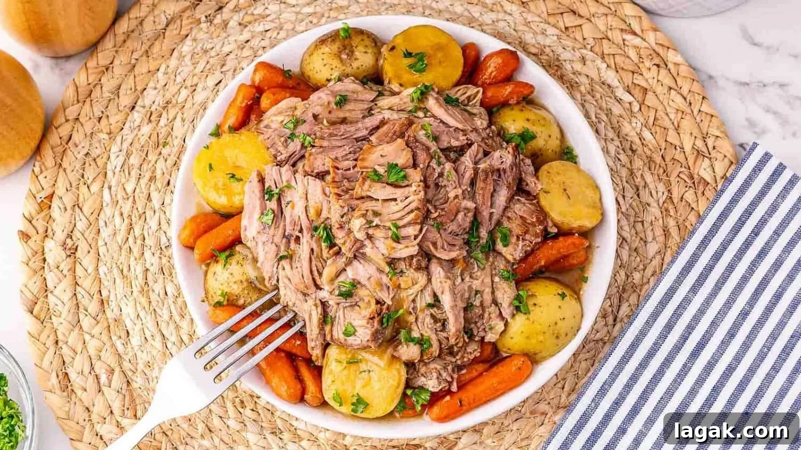 21 Slow Cooker Dinners for Stress-Free Weeknight Meals 13 A bowl of shredded pot roast with baby potatoes and carrots, garnished with parsley, on a woven placemat.