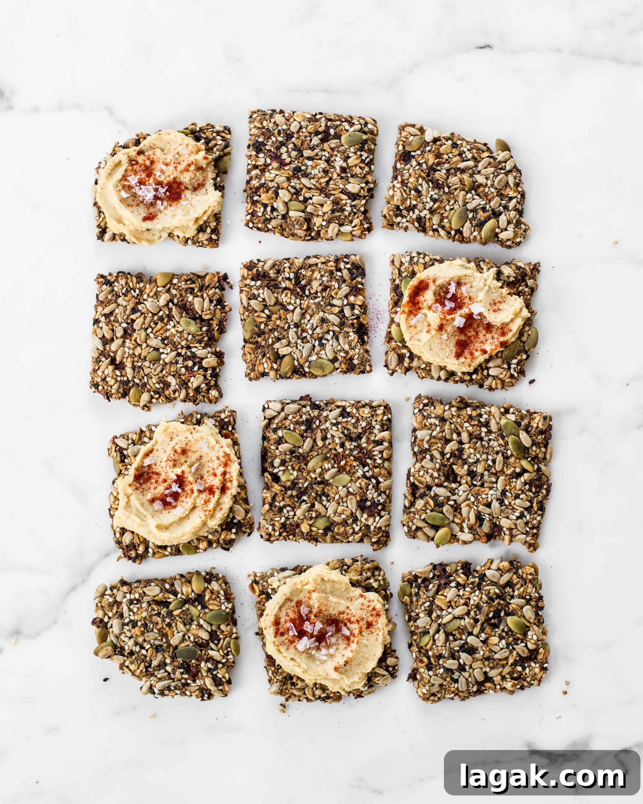 Crunchy Super Seed Crackers Recipe for Homemade Snacks 2 12 Seed crackers arranged in a rectangle. 4 of them topped with hummus.