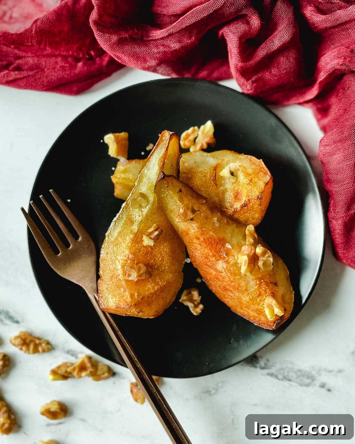Air Fryer Cinnamon Pears Recipe 2 Air fryer pears sit on a black plate topped with walnuts.