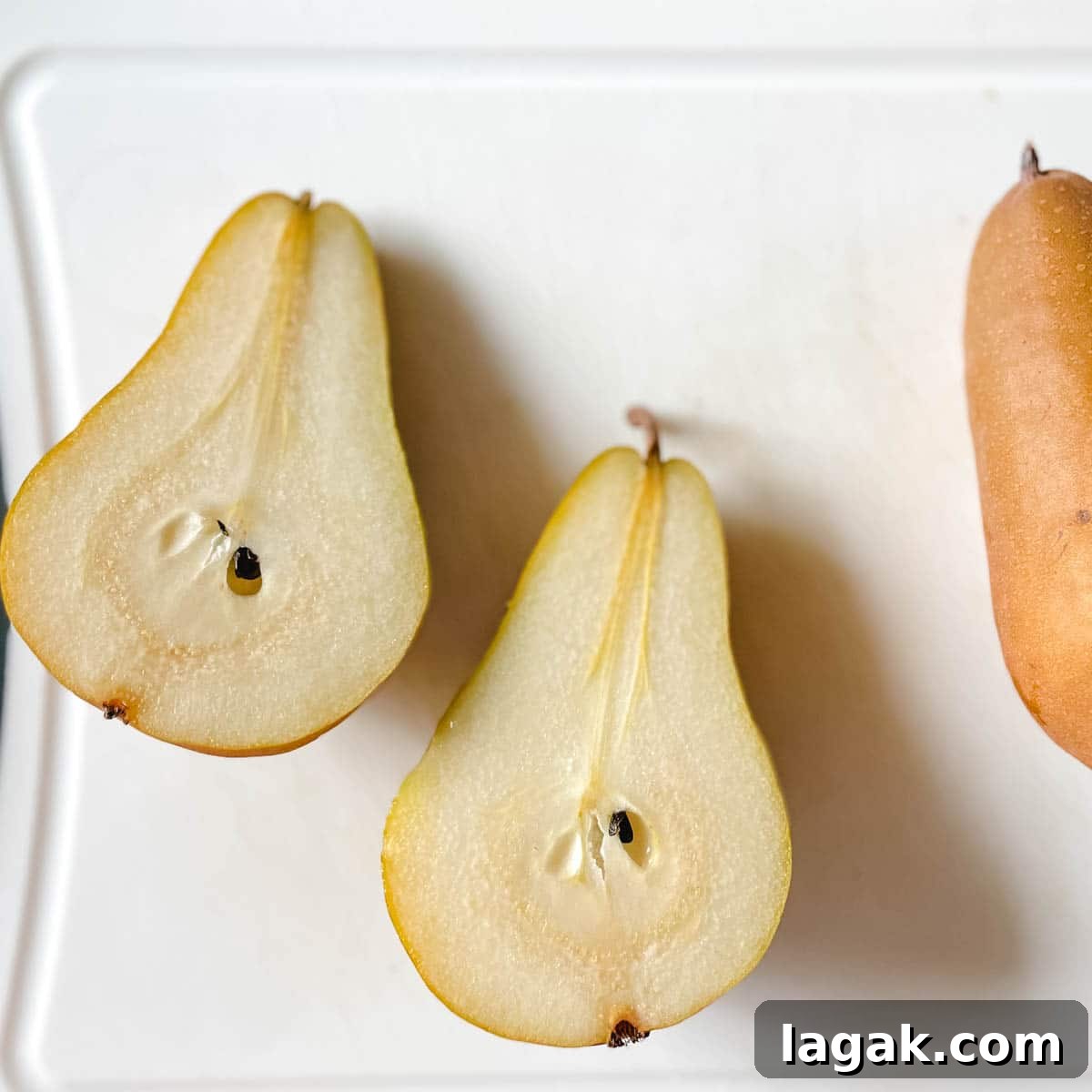 Air Fryer Cinnamon Pears Recipe 4 Image shows a halved pear on a white cutting board.