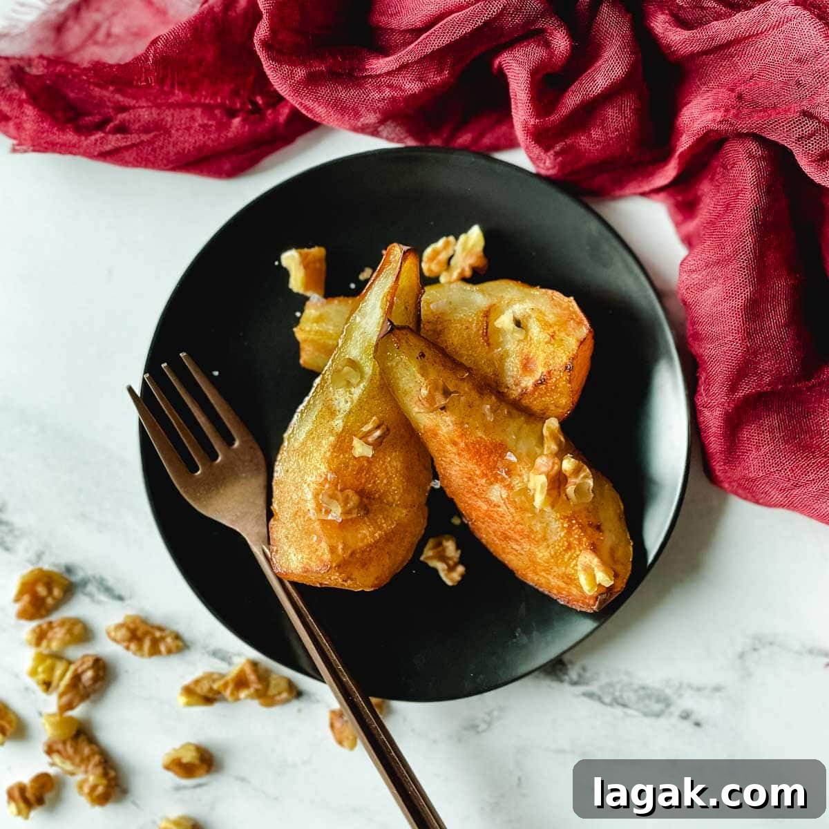 Air Fryer Cinnamon Pears Recipe 9 Air fryer pears sit on a black plate topped with walnuts.