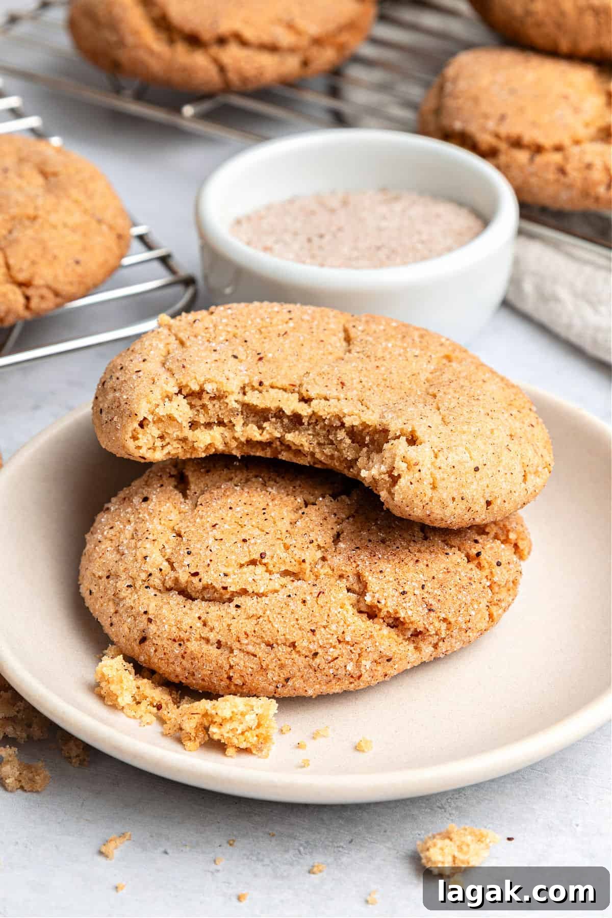 Chewy Browned Butter Snickerdoodle Cookies Recipe 11 Light pink plate with whole and bitten cinnamon snickerdoodle cookies. Bowl with sugar.