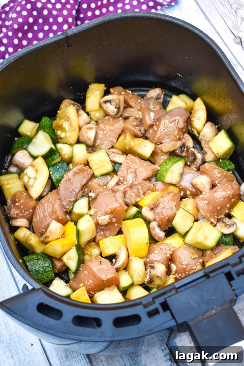 uncooked air fryer hibachi chicken and vegetables ingredients in an air fryer basket