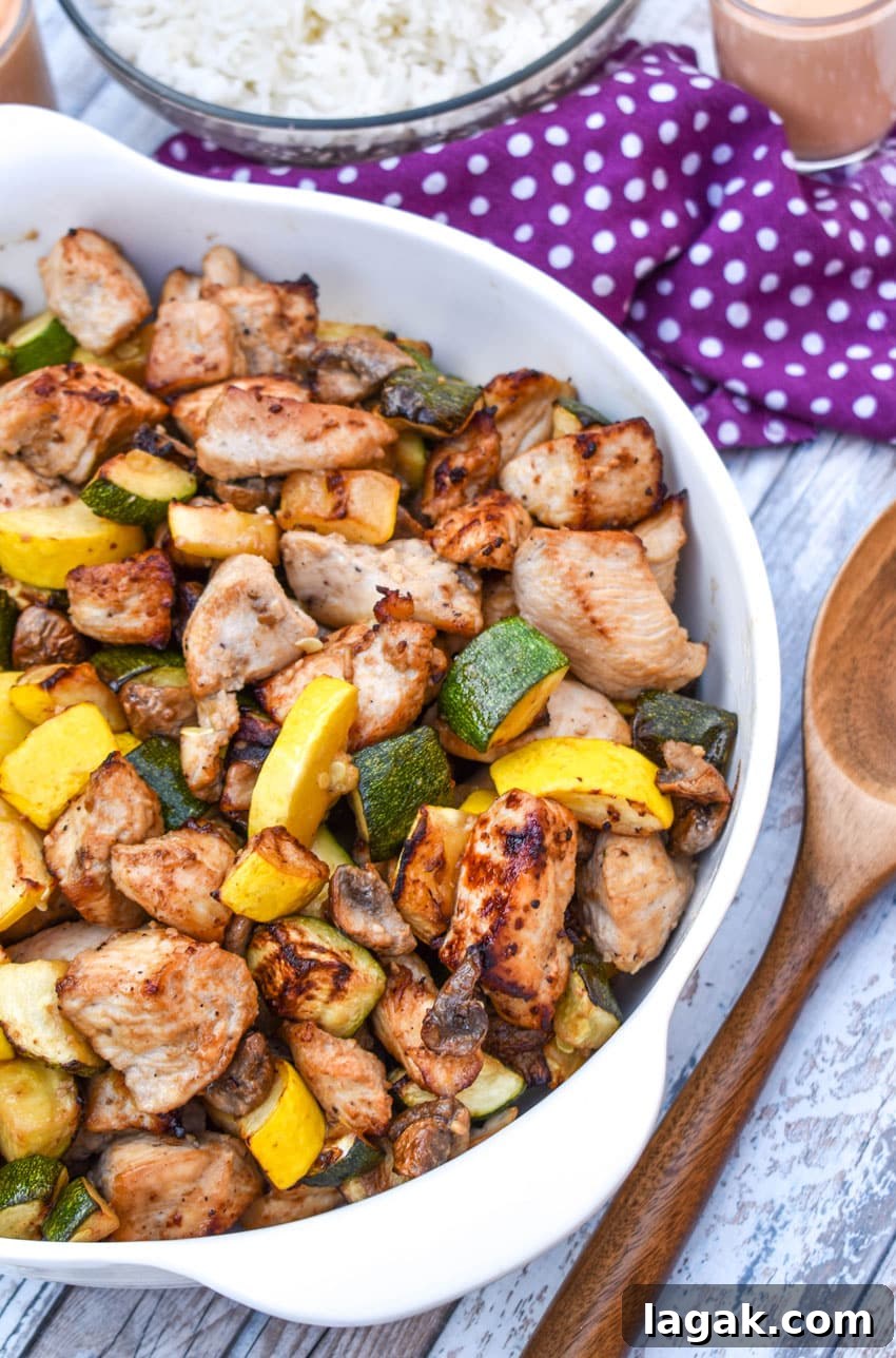 easy homemade hibachi chicken and vegetables in a white serving bowl with a wooden spoon on the side