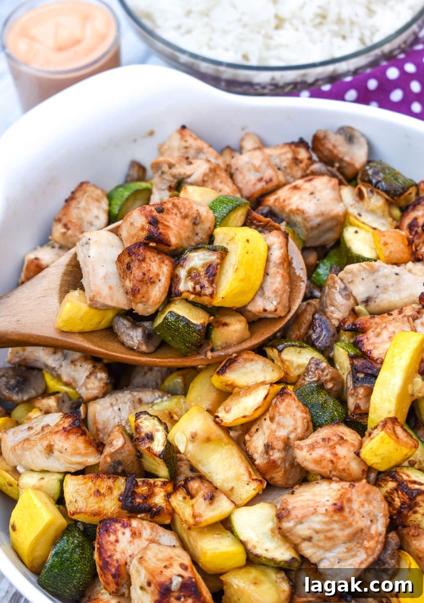 a wooden spoon scooping easy homemade hibachi chicken and vegetables out of a large white bowl
