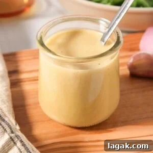 Garlic Parmesan Dressing Recipe for Salads and Veggies 11 A small glass jar of sherry shallot dressing with a spoon on a wooden board.