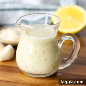 Garlic Parmesan Dressing Recipe for Salads and Veggies 12 Garlic parmesan dressing in a glass container with lemon and garlic on a wooden board.