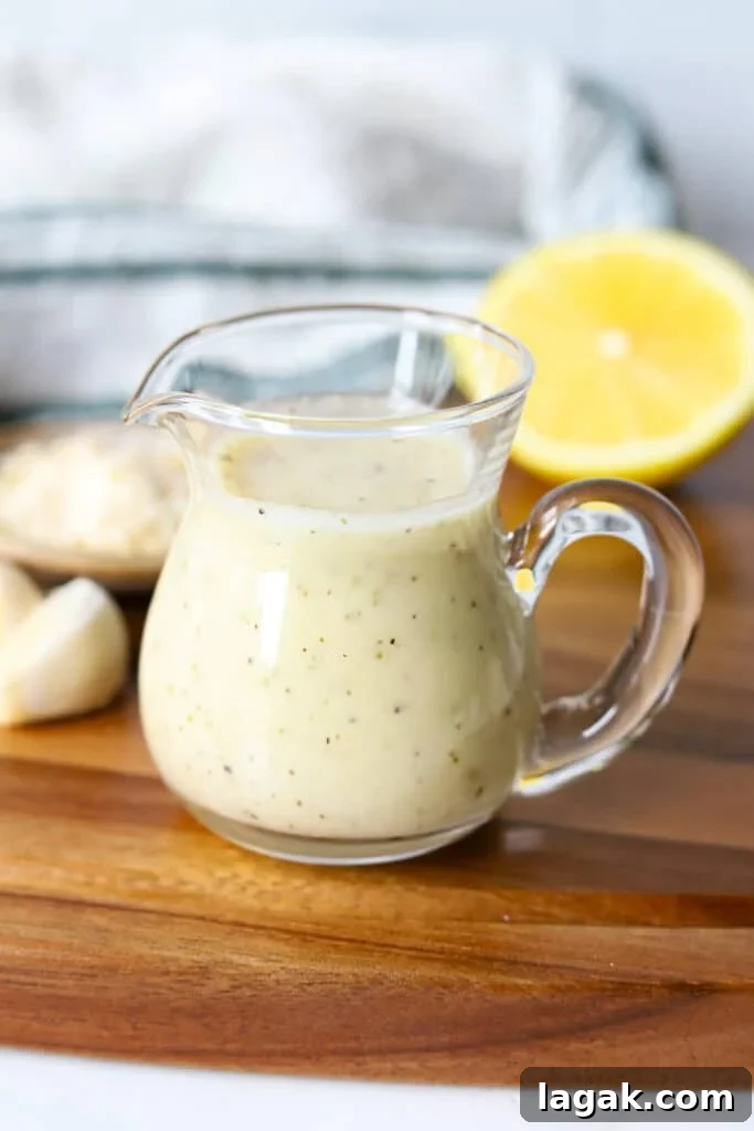 Garlic Parmesan Dressing Recipe for Salads and Veggies 6 Garlic parmesan dressing in a glass container with lemon and garlic on a wooden board.