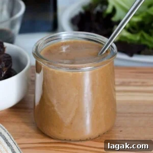 Garlic Parmesan Dressing Recipe for Salads and Veggies 9 A clear glass jar of balsamic date dressing with a spoon.