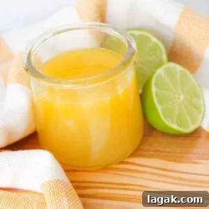 Garlic Parmesan Dressing Recipe for Salads and Veggies 10 A small jar of honey lime vinaigrette with two lime halves on a wooden board.