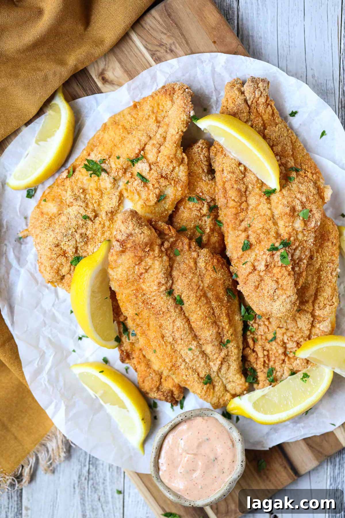 Crispy Oven-Baked Catfish with Garlic and Lemon 2 southern oven fried catfish on a wooden cutting board.